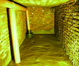 Gemauerte Regenwasser-Zisterne - Innenansicht unverputz mit Lehmboden und beruhigtem Einlauf.